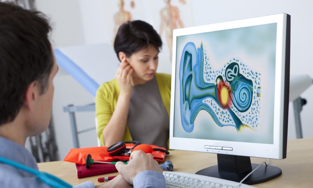 Médico revisa el aparato auditivo en un ordenador